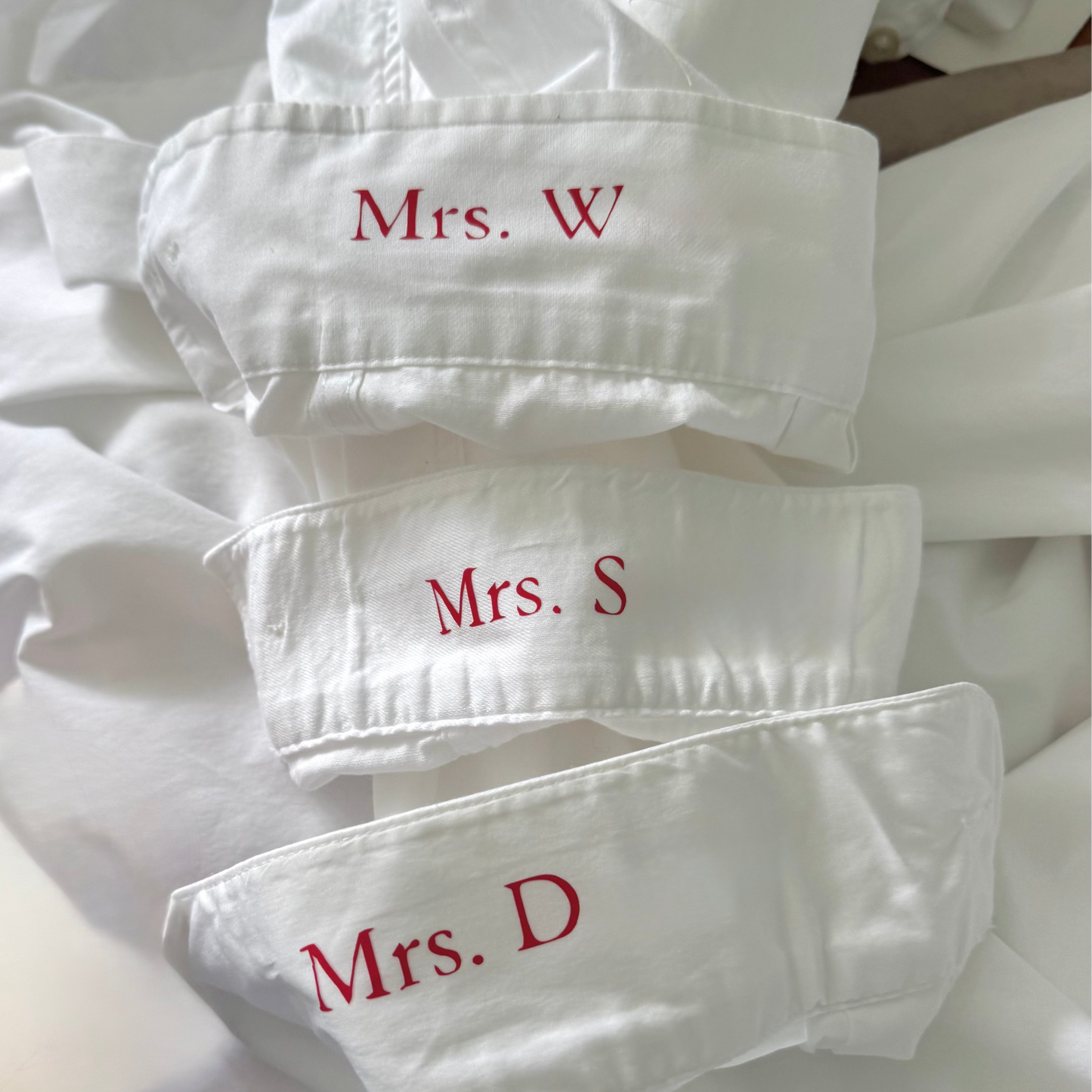 Stack of white shirts with red text on a neutral background