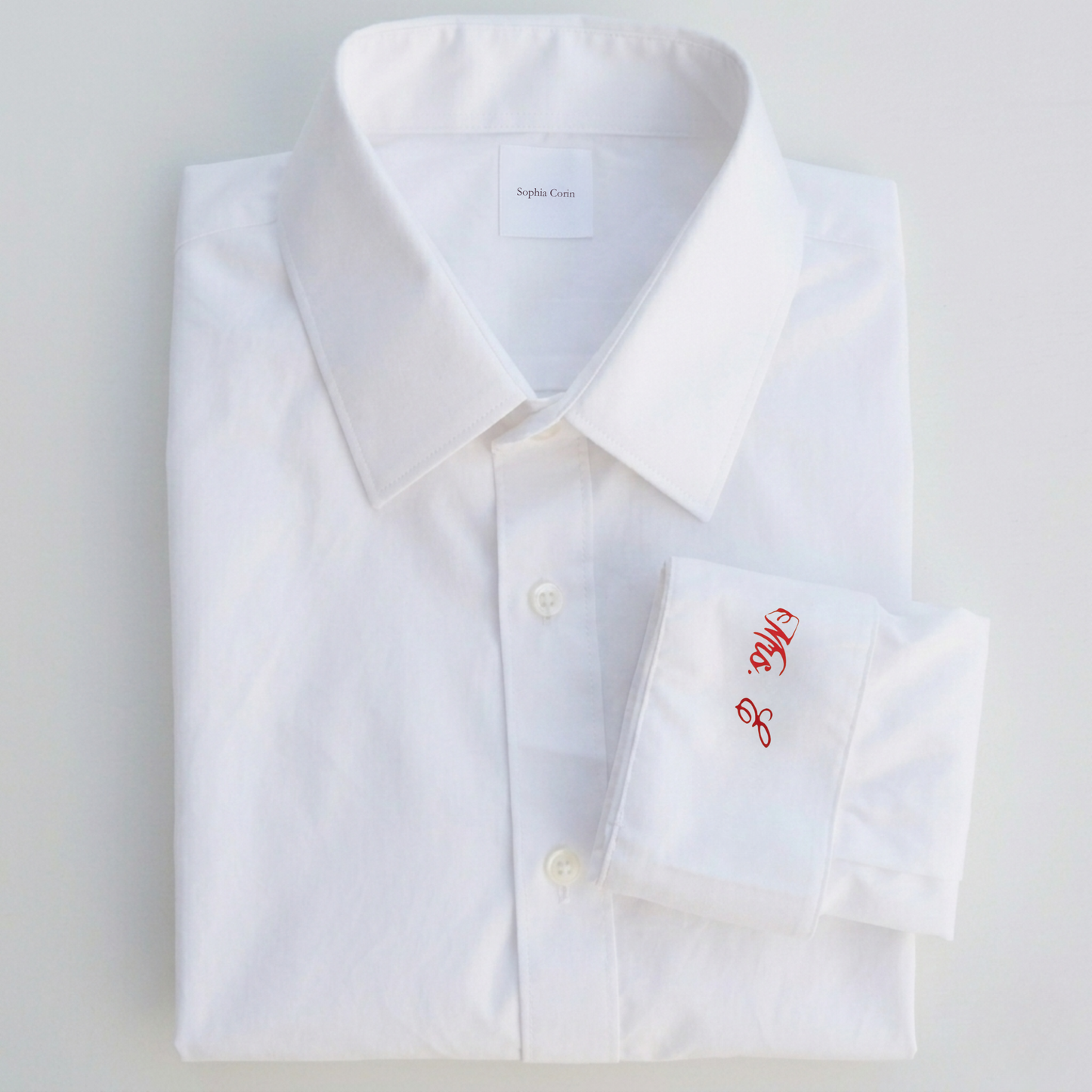 White dress shirt with red monogram on a light gray background