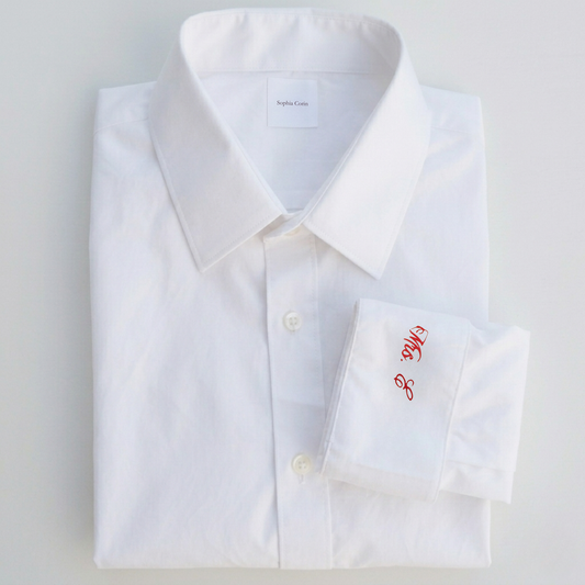 White dress shirt with red monogram on a light gray background
