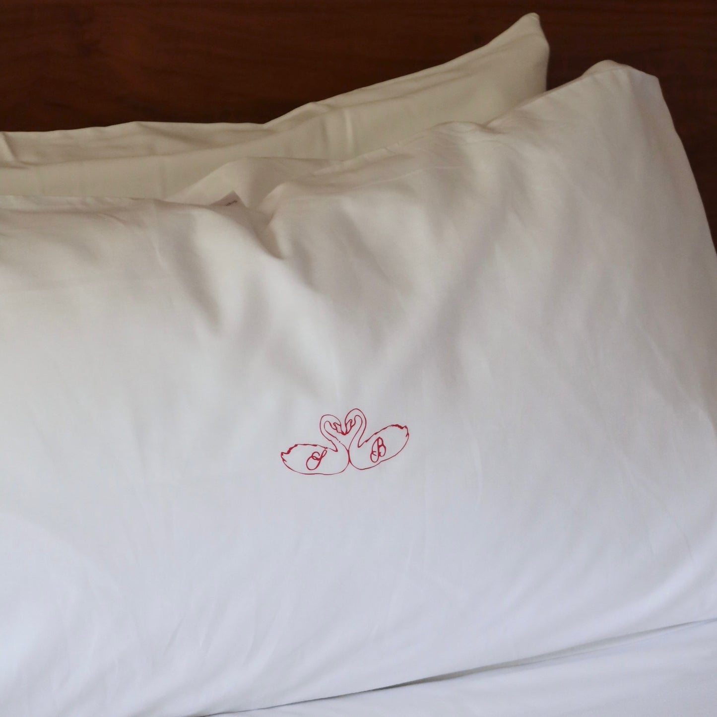 White pillowcases with red floral embroidery on a wooden surface