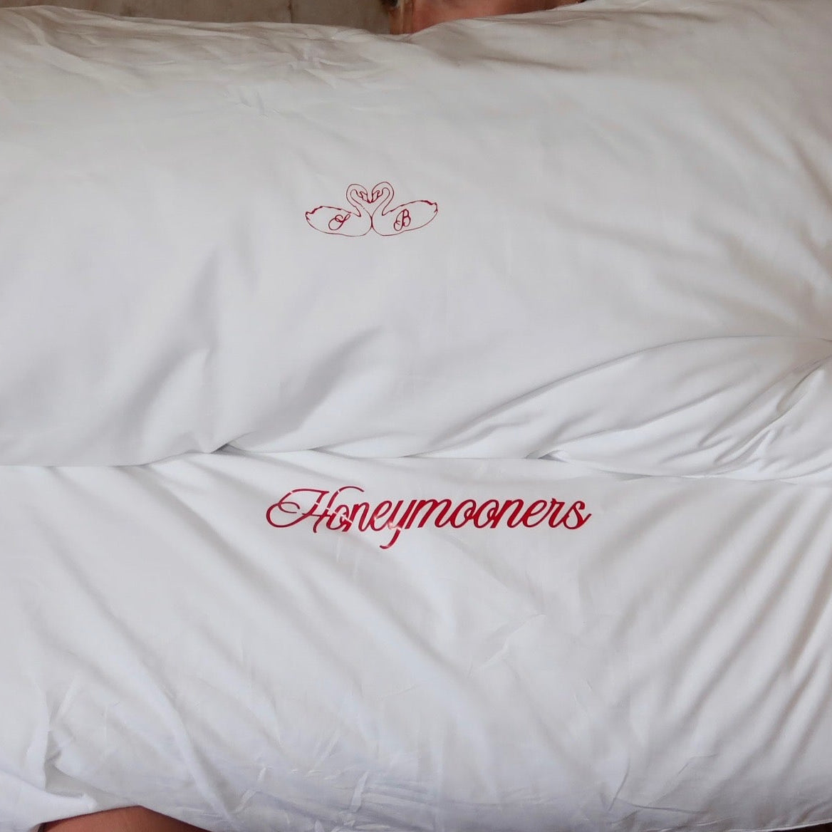 Person holding a large white comforter with 'Honeymoons' branding.