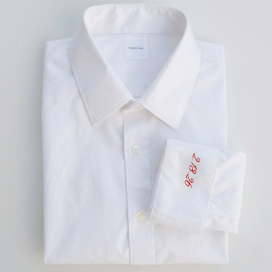 White dress shirt with red monogram on a light gray background